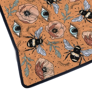 Macro detail of flannel blanket edge featuring soft bees and poppy flower patterns