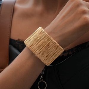 Macro detail of wide golden layered coil cuff bracelet worn on female wrist for a chic look