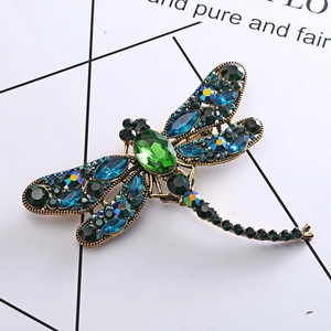 Detailed close-up of a vintage dragonfly brooch with emerald stones and colored crystals