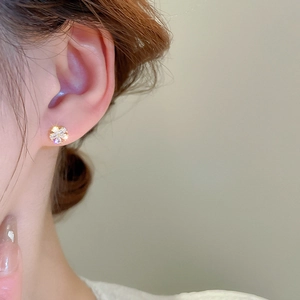 Gros plan de boucles d'oreilles fleurs dorées avec zircons blancs sur une femme