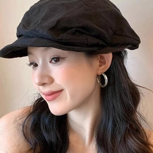 Close-up of model wearing a stylish black newsboy hat and large silver hoop earrings