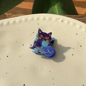 Detail of a mini cat hair claw in blue-purple marble acetate with golden outlines