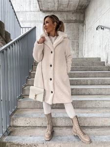 Close-up of oatmeal teddy coat with lapels and black buttons on a city street