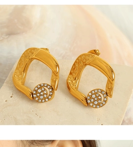 Detail of gold hollow geometric earrings with pavé white zircon drop on stone base