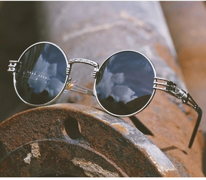 Macro shot of silver steampunk round sunglasses with grey lenses on industrial pipe