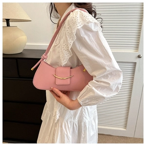 Close-up of pink leather baguette bag with crescent metal detail and knotted shoulder strap