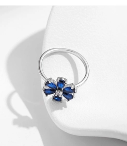 Detailed view of S925 silver flower ring with teardrop blue sapphire on ceramic stand