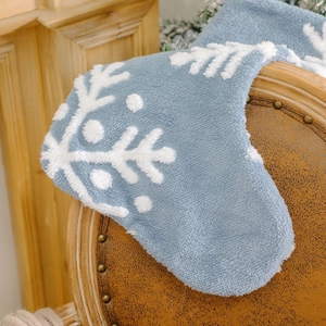 Blauer Plüsch-Weihnachtsstrumpf mit weißen Schneeflocken auf einem Vintage-Lederstuhl