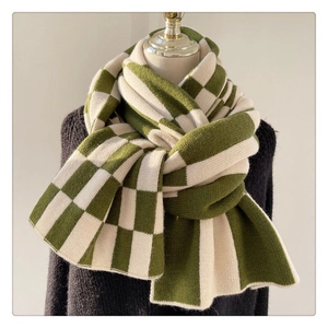 Detailed texture of green and beige checkerboard knit scarf on a black sweater