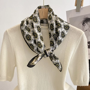Elegant paisley satin square scarf in black, white, and gold on a white knit sweater