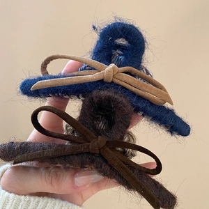 Vue détaillée de pinces à cheveux en peluche bleu marine et marron avec nœud en daim