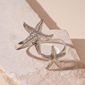 Detail of silver starfish arm cuff with textured surface on natural stone background