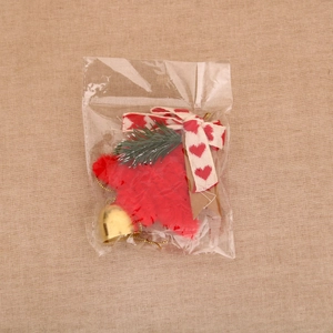 Close-up of red plush Christmas bell hanging with pine needles and ribbon bow