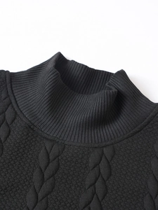 Close-up of the black knitted sweater featuring a ribbed turtleneck and cable knit texture