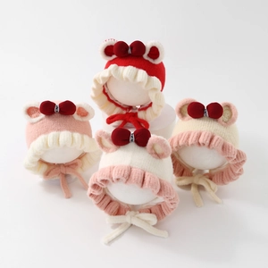 Detail view of knitted baby earflap hats with lace trim, bows and ties in four colors