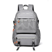 Détail d'un sac à dos gris avec fermetures éclair orange et poches filet latérales