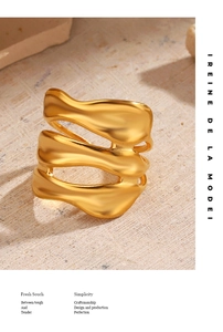 Detail of a wide irregular wavy gold open ring on a natural stone background