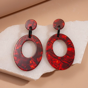 Detail view of retro red resin earrings with black tortoiseshell texture on stone