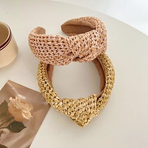 Gros plan de serre-têtes en paille noués rose et jaune avec texture tressée
