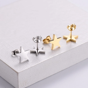 Star-shaped stainless steel stud earrings in gold and silver on white stone base