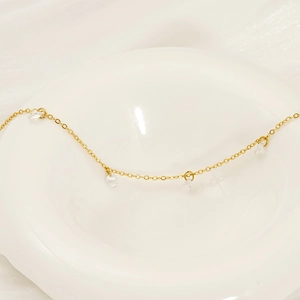 Sparkling 18k gold plated titanium bracelet with clear zircon stones on a white ceramic plate