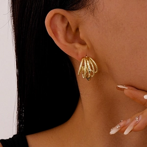 Macro detail of layered gold-plated C-shaped hoop earrings on a model's ear lobe