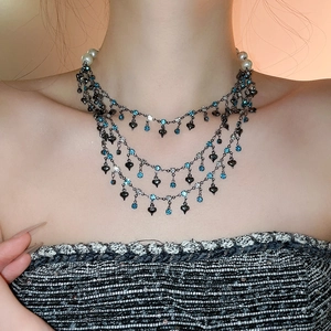 Detail of multi-layer black metal necklace with blue rhinestones and pearl clasp