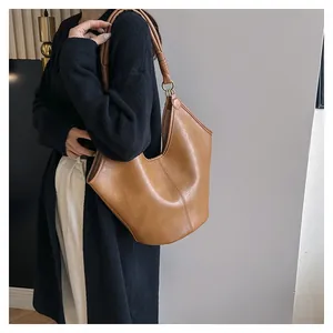 Detail of the brown PU leather tote showing textured finish and hand-wrapped handle knots