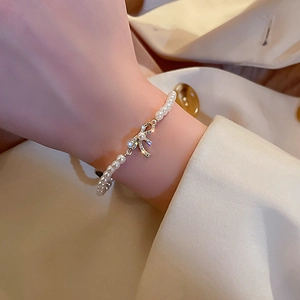 Close-up of a bow pearl bracelet with gold plating on a woman's wrist in a French style