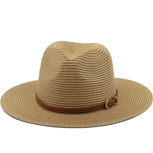 Detail view of the hand-woven texture and brown leather strap with gold buckle on a straw hat