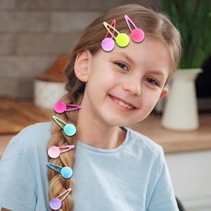 Close-up of colorful plush pom-pom hair clips worn by a young girl in a cozy setting