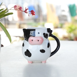 Macro detail of cow-shaped ceramic coffee mug featuring 3D ears and pink snout handle