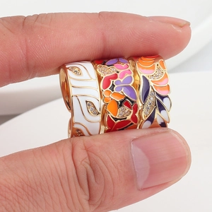 Detail of colorful enamel flower and butterfly rings with cubic zirconia inlay on gold plating