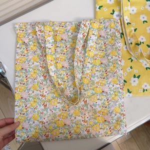 Flat lay of a large floral cotton canvas tote bag with dense yellow and pink flower patterns