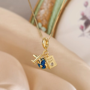 Gold plated necklace with small airplane, blue globe and passport pendant on silk cloth