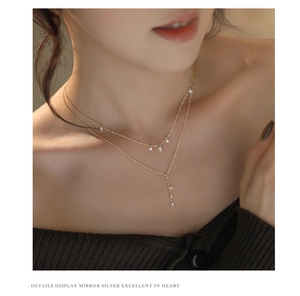 Close-up of double-layer gold necklace with sparkling zircon pendants on a model