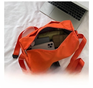 Detail view of large internal capacity for orange nylon crossbody bag with daily essentials