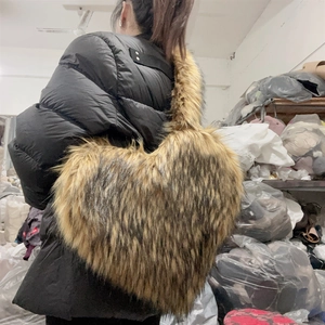 Detail view of heart-shaped faux raccoon fur crossbody bag with fluffy texture