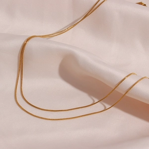 Close-up of 18K gold plated double-layer herringbone chain on pink silk fabric