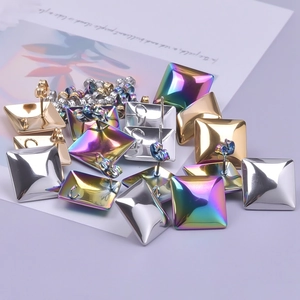 Macro view of square geometric stainless steel studs in gold, silver, and rainbow finishes