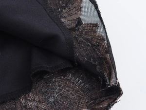 Detail van zwarte mesh zoom met bruin bloemenborduurwerk op een nauwsluitende jurk
