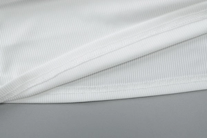 Détail du tissu en maille côtelée blanche et coutures de précision sur ce haut en V