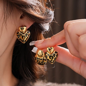 Luxurious gold plated heart earrings with leopard print pattern worn by a model