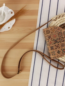 Bohemian round straw crossbody bag with geometric ethnic pattern on natural woven fiber