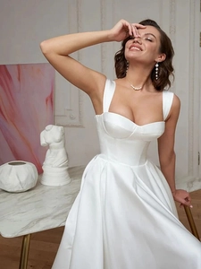 Detail of elegant white satin wedding dress featuring wide straps and a sweetheart neckline