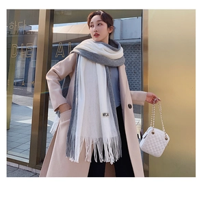 Detail of grey and white knit scarf with fringe and small NPCAB label on model