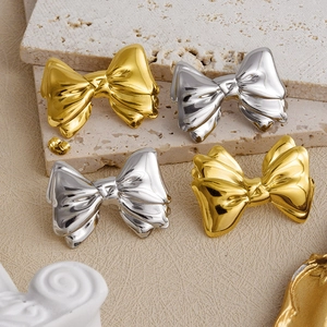 Detailed view of gold and silver bow stud earrings with textured metallic finish