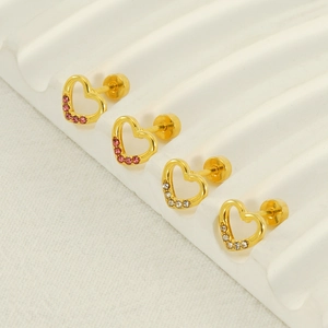 Golden hollow heart stud earrings set with pink and clear crystals on a ceramic tray