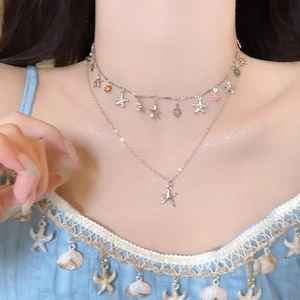Gros plan d'un collier argenté à double épaisseur avec pendentifs étoiles et fleurs colorées