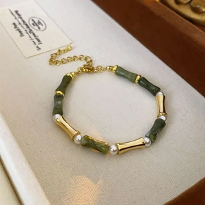 Detail of bamboo-style jade bracelet with gold accents and pearls in a jewelry box